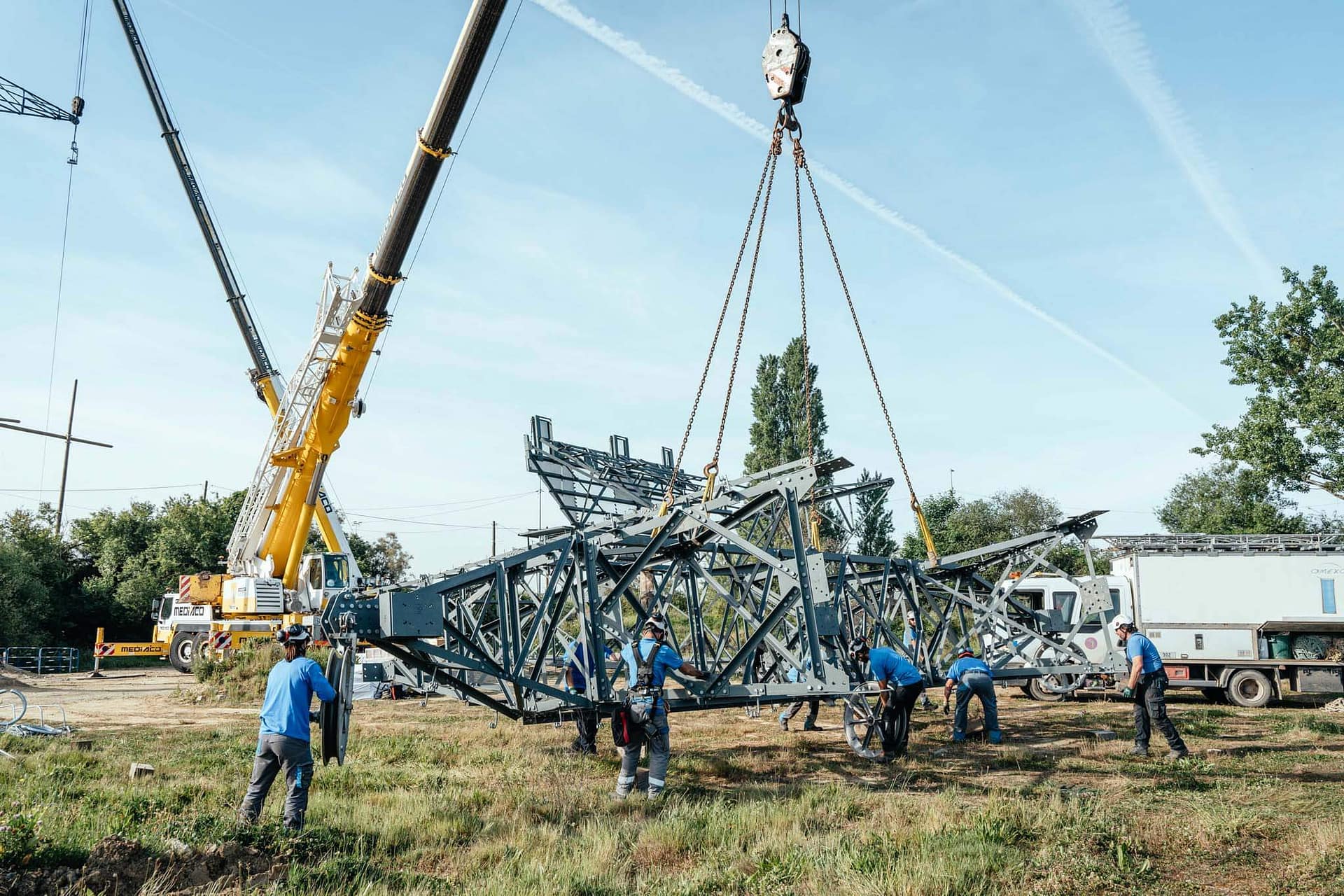 Il faut plusieurs grues et de nombreux bras pour manipuler ces monstres de métal que sont les pylônes électrique de RTE