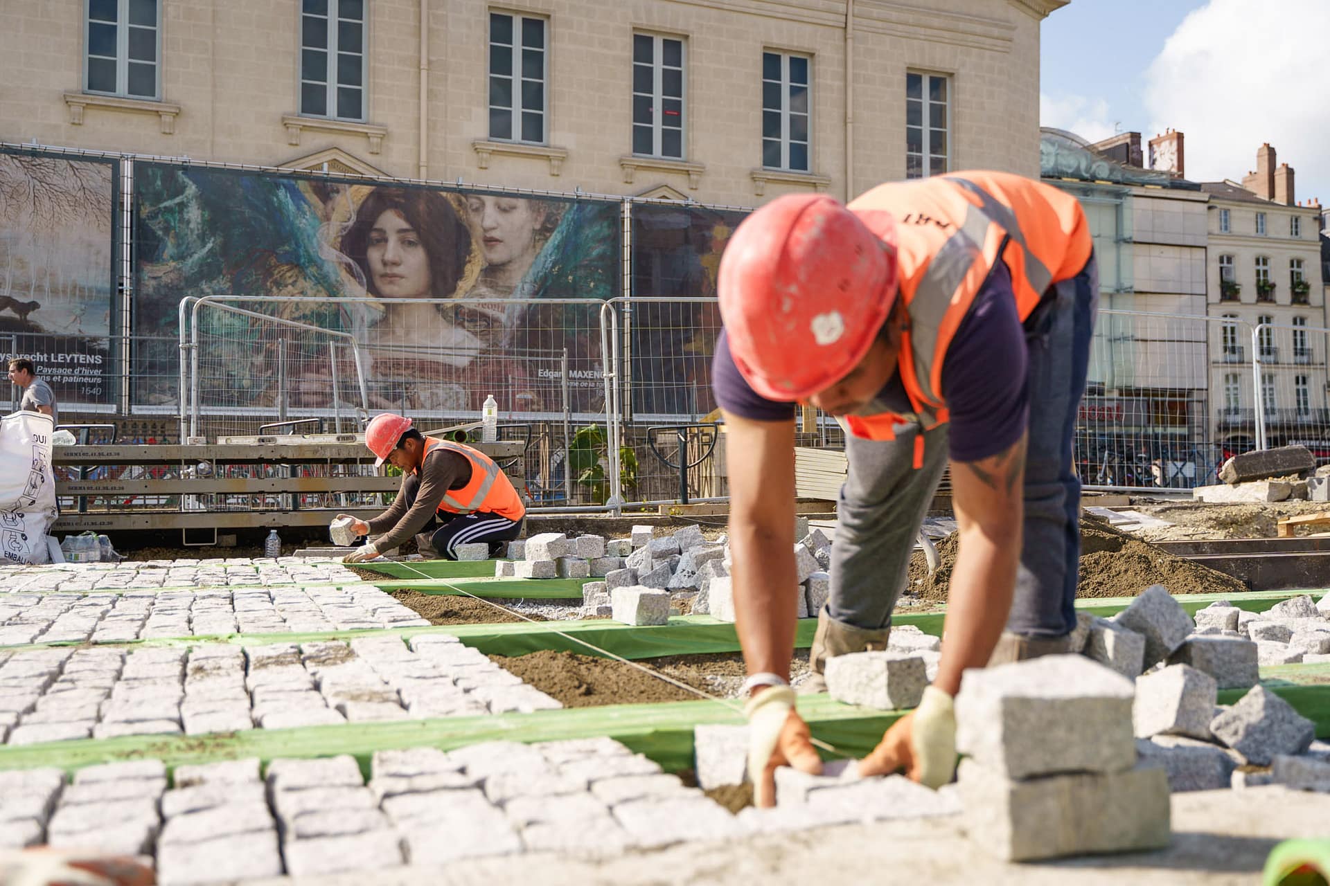 Des ouvriers posent les nouveaux pavés le long de la ligne de tramway dans le centre ville de nantes